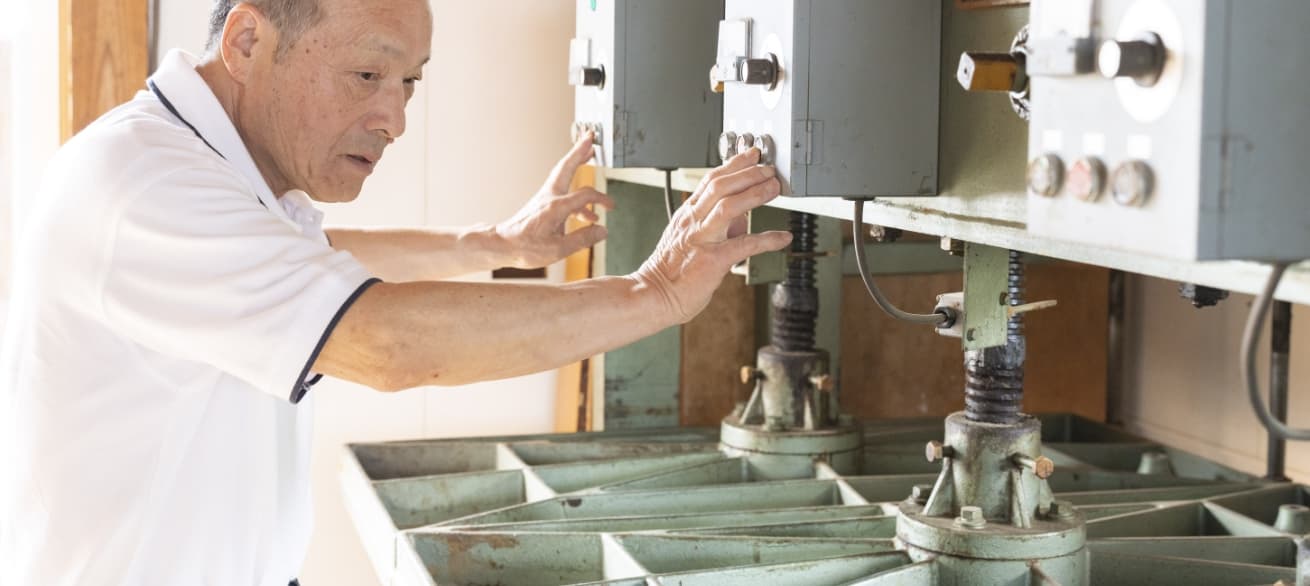 職人が、ウールボードをプレス機にかける様子