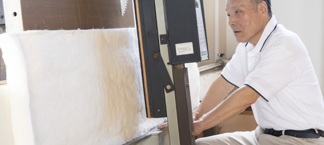 職人が、ウールボードを大型パネルソーで裁断する様子