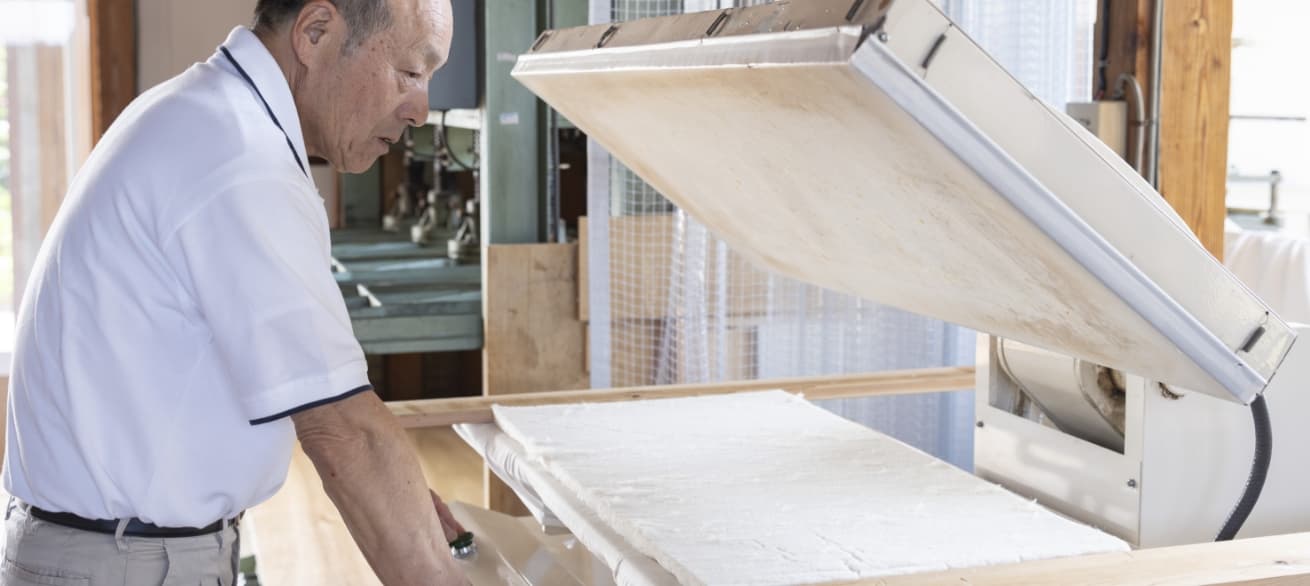 職人が、裁断されたものを蒸気プレスし、絨毯状マット加工する様子